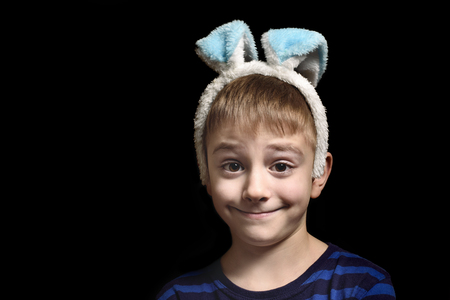 Funny blond boy in ears of ear against a black background. Close-up portrait.の写真素材