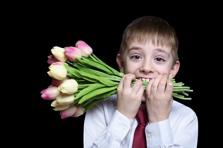 Boy in shirt and tie holding a bouquet of tulips in the teeth. Isolate on black backgroundの写真素材