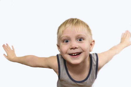 Joyful blond boy in shirt standing arms to the side. Isolate on white backgroundの写真素材