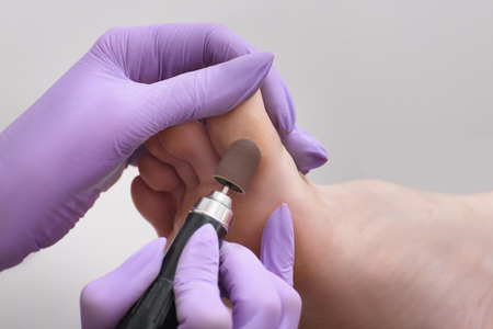 Foot skin treatment process. Gloved hands with a pedicure machine. Close-upの写真素材