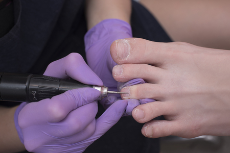 Processing toenails, pedicure. Gloved hands with a pedicure cutter. Close-upの写真素材
