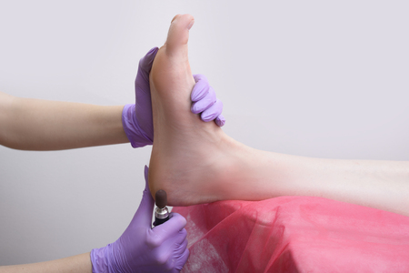 Foot skin treatment process. Gloved hands with a pedicure machine. Close-upの写真素材