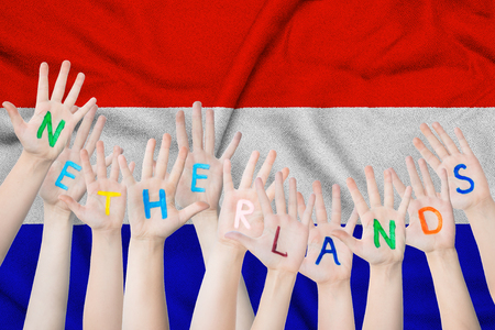 Netherlands inscription on the children's hands against the background of a waving flag of the Netherlands.の写真素材