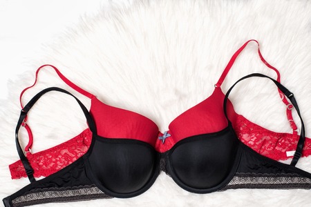 Black and red bra on white fur. Flat lay. Fashion concept.