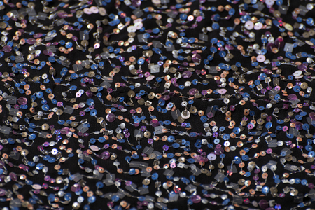 Texture of black cloth with colorful sequins. Close-up.