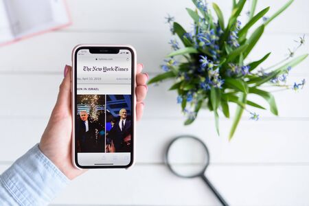 KHARKIV, UKRAINE - April 10, 2019: Apple iPhone X in female hand with nytimes.com site on the screen.のeditorial素材