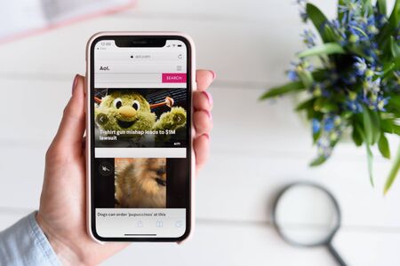 KHARKIV, UKRAINE - April 10, 2019: Woman holds Apple iPhone X with Aol.com site on the screen.のeditorial素材