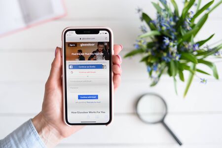 KHARKIV, UKRAINE - April 10, 2019: Woman holds Apple iPhone X with glassdoor.com site on the screen.のeditorial素材