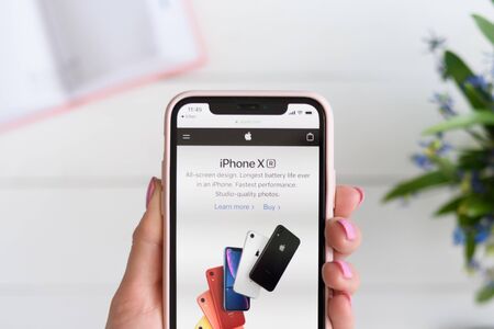 KHARKIV, UKRAINE - April 10, 2019: Woman holds Apple iPhone X with apple.com site on the screen.のeditorial素材