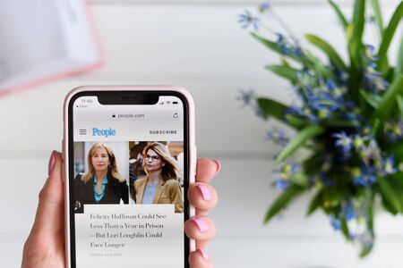 KHARKIV, UKRAINE - April 10, 2019: Woman holds Apple iPhone X with people.com site on the screen.のeditorial素材