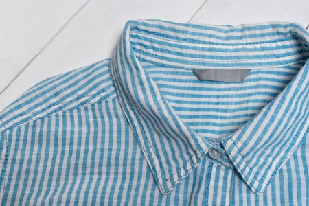 Label on blue striped cotton shirt. Fashion concept. Close up