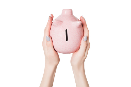 Pink piggy bank in female hands isolate on white background. View from above.の写真素材