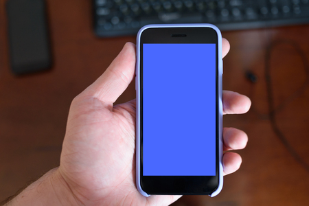 Male hand with a smartphone. Black blank screen. Home backgroundの写真素材