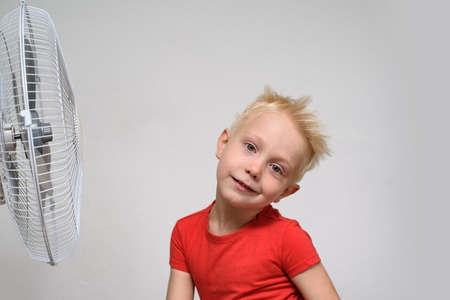 Pretty blond boy in red shirt enjoying the cool air. Summer concept.の写真素材