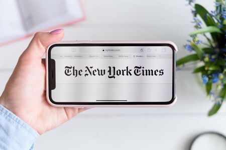 KHARKIV, UKRAINE - April 10, 2019: Apple iPhone X in female hand with nytimes.com site on the screen. Horizontal viewのeditorial素材