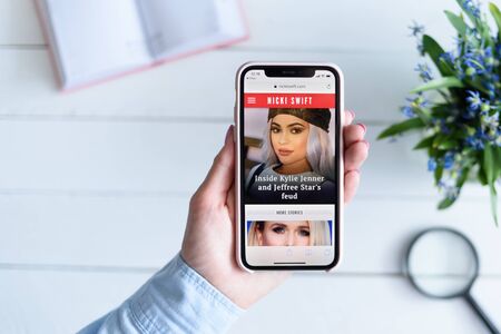 KHARKIV, UKRAINE - April 10, 2019: Apple iPhone X in female hand with nickiswift.com site on the screen.のeditorial素材