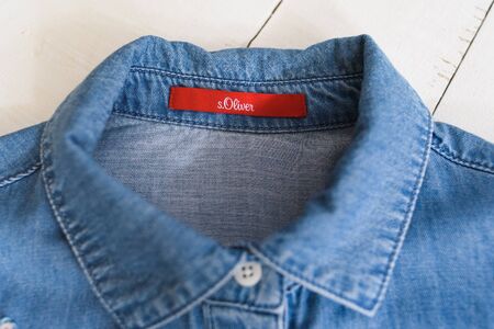 KHARKOV, UKRAINE - APRIL 27, 2019: Red label s.Oliver on blue denim shirt. Clothes concept. Detailsのeditorial素材