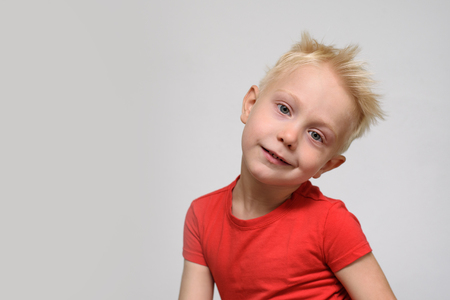 Little smiling blonde boy in red t-shirt. Portrait. Space for text. White backgroundの写真素材