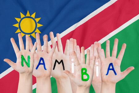 Inscription Namibia on the children's hands against the background of a waving flag of the Namibiaの写真素材
