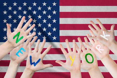 Inscription New York on the children's hands against the background of a waving flag of the USAの写真素材