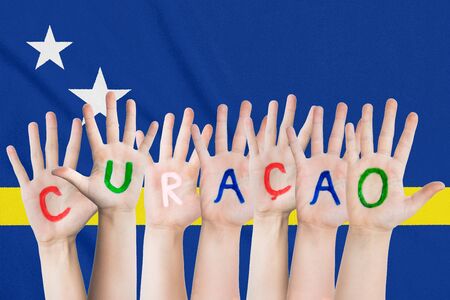 Inscription Curacao on the children's hands against the background of a waving flag of the Curacaoの写真素材