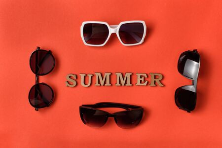 Word Summer from wooden letters. Four sun glasses on live coral background. Travel conceptの写真素材