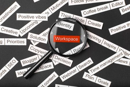 Magnifier glass over the red inscription workspace cut out of paper. Surrounded by other inscriptions on a dark background. Word cloud concept.の写真素材
