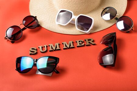 Word Summer from wooden letters. Five sun glasses, part of a hat. Live coral background. Travel conceptの写真素材