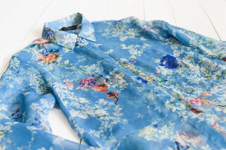 KHARKOV, UKRAINE - APRIL 27, 2019: Details of blue floral blouse. Clothes concept. Wooden background.のeditorial素材