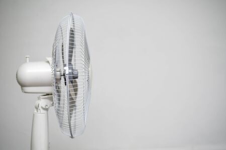 Floor fan standing on a gray wall background.