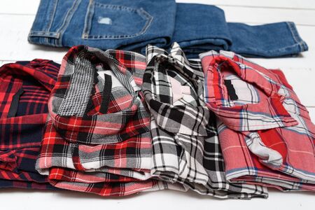 Plaid shirts and blue jeans on a white wooden background. clothing concept.
