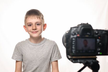 Schoolboy is ready to give the interview on a camcorder. Young video blogger. White backgroundの写真素材