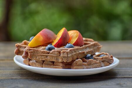 Chocolate Belgian waffles with fruits on green background. Delicious breakfast.の写真素材