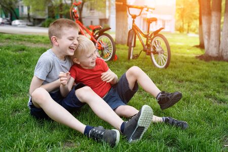 Two laughing boys having fun on the grass. Bicycles in the backgroundの写真素材
