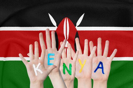 Inscription Kenya on the children's hands against the background of a waving flag of the Kenyaの写真素材