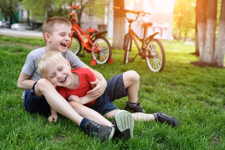 Two laughing boys having fun on the grass. Bicycles in the backgroundの写真素材