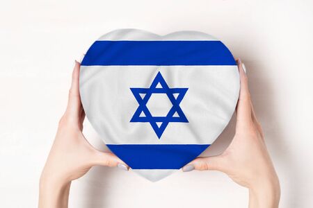 Flag of Israel on a heart shaped box in a female hands. White backgroundの写真素材