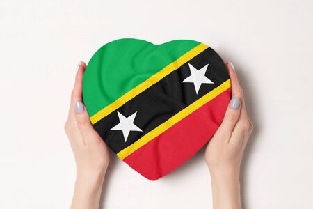 Flag of Saint Kitts and Nevis on a heart shaped box in a female hands. White backgroundの写真素材