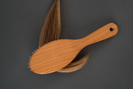 Curl of blond and a massage comb. Black background. Close-up