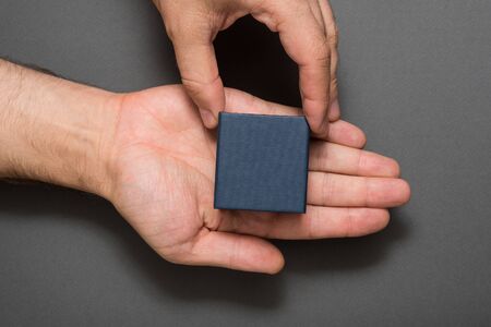 Male hands with a black square box. Present. Black backgroundの写真素材