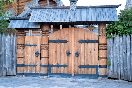 Vintage wooden gate with wrought iron elements and a picket fenceの写真素材