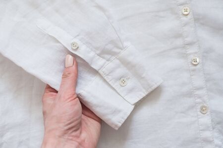 Sleeve of white shirt in female hand. Clothes concept. Details of clothesの写真素材