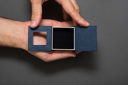 Open empty black jewelry box in a male hands. Present. Black background
