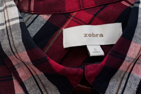 KHARKIV, UKRAINE - September 19, 2019: White Zebra label on the red plaid shirt. Close-upのeditorial素材