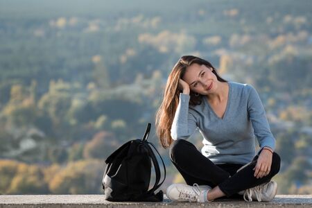 Portrait of a smiling beautiful girl with a backpack outdoors. Sunny day