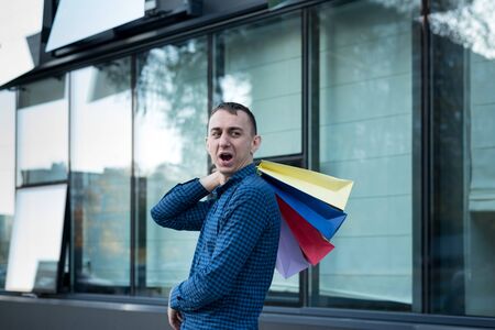 Happy young man with colorful shopping bags on the street. Mall on backgroundの写真素材