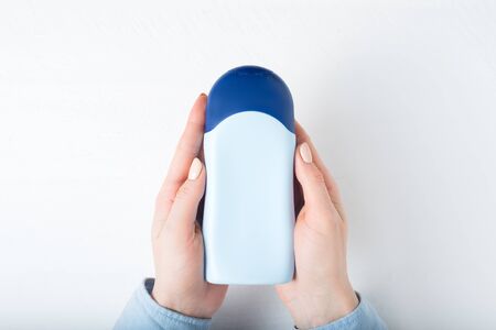 Blue bottle for cosmetic product in a female hands. White backgroundの写真素材