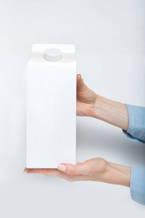 White carton box or packaging with a cap in a female hands. White backgroundの写真素材