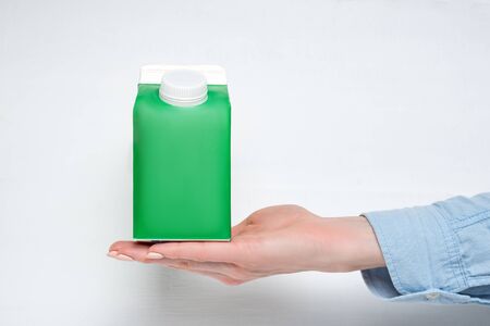 Green carton box or packaging with a cap in a female hand. White backgroundの写真素材