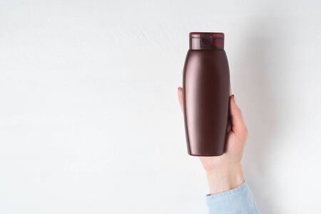 Brown bottle for cosmetic in a female hand. Mockup. White backgroundの写真素材